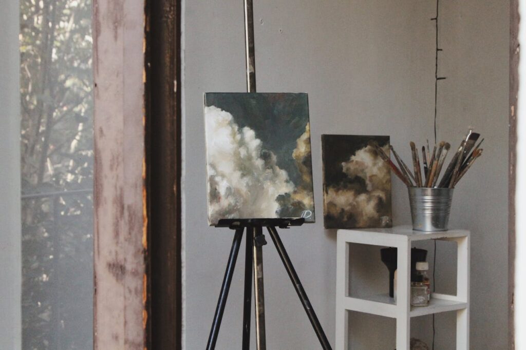 Demo Post 1 Cozy art studio featuring cloud paintings on easels and paintbrushes, captured indoors.