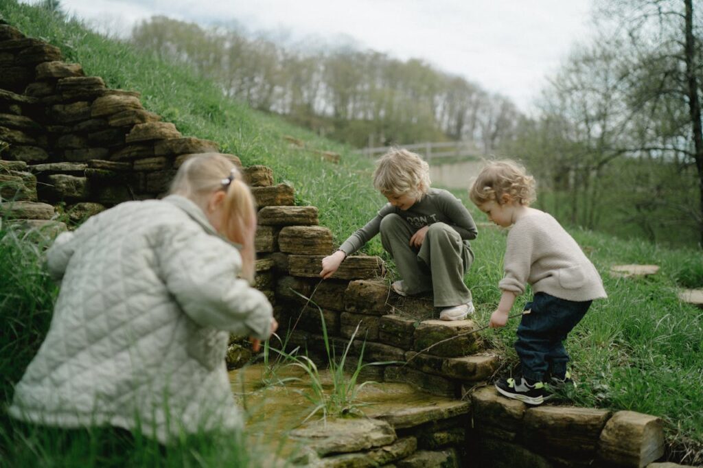 A group of children playing by a small natural spring outdoors, emphasizing exploration and nature play.